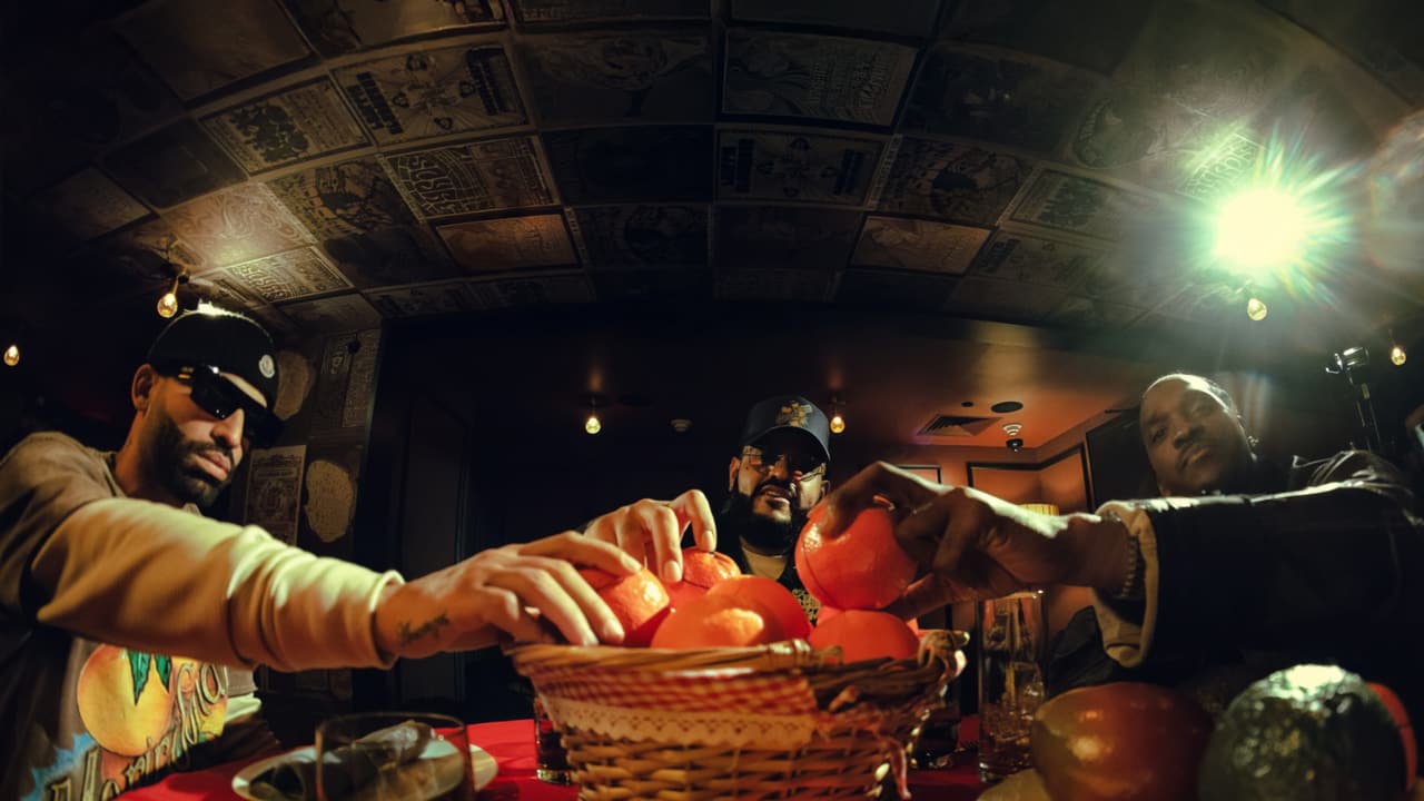 Three men reaching together into a gingham-lined basket of oranges on a red tablecloth, a vintage-concert-poster ceiling arching above them