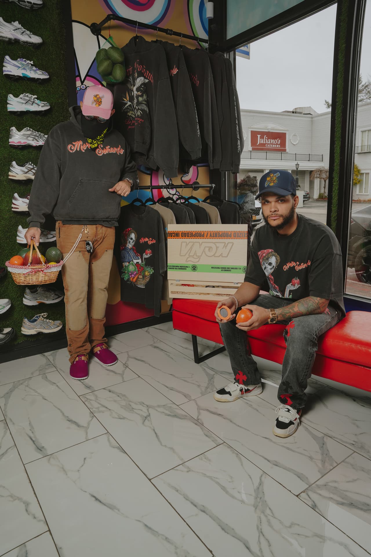 Two men in a sneaker store, one masked in the harvest hoodie and pink hat holding a basket, one seated in the harvest tee