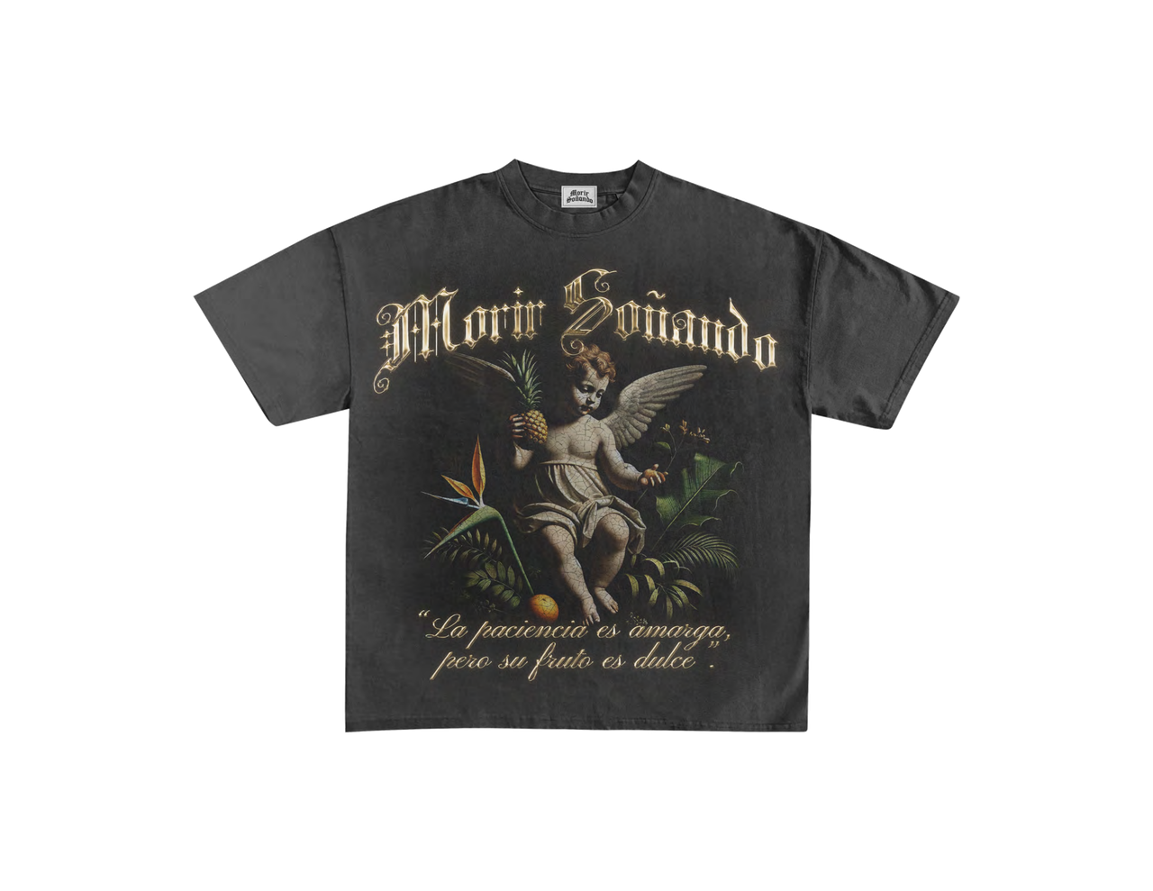 Black t-shirt mockup with a stone cherub holding a pineapple among palm leaves and a bird-of-paradise flower, under blackletter 'Morir Soñando'
